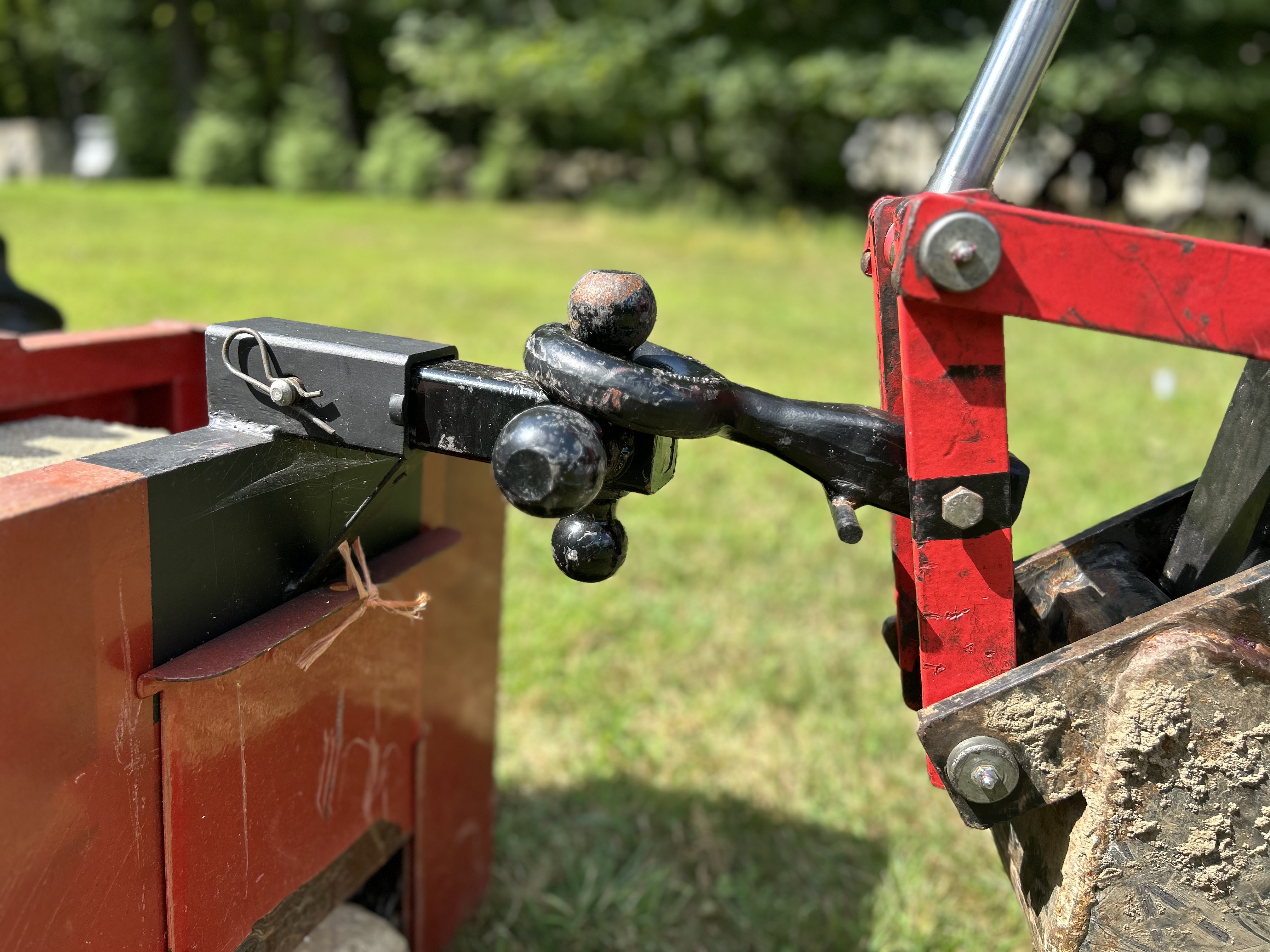 Close up of tow loop on Harbor Freight Backhoe Trencher attached to a ball hitch on a ballast box